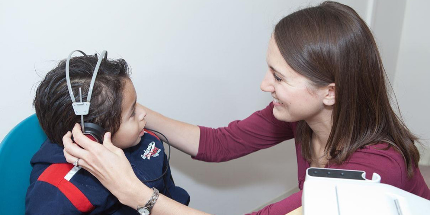 Student putting headphones on a child